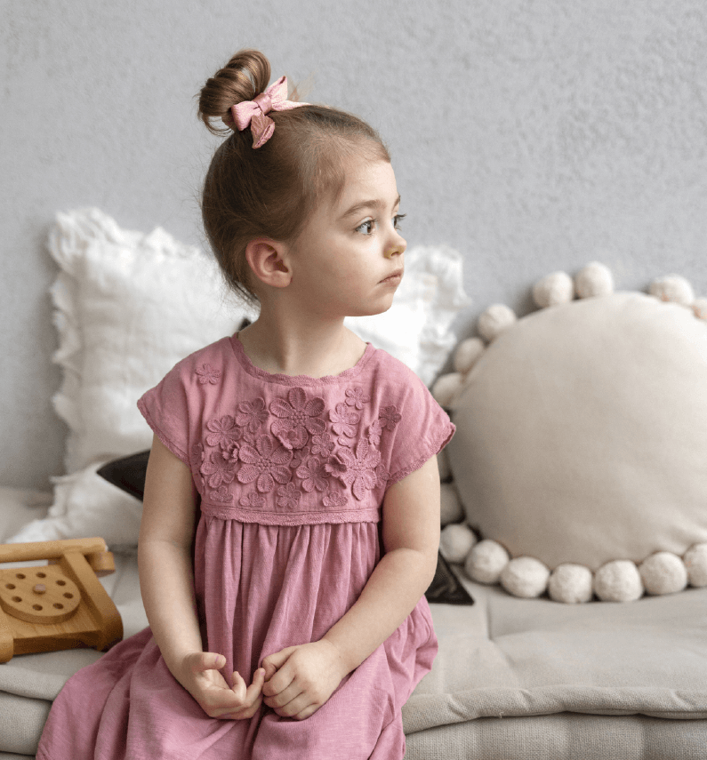 A Middle Eastern child in a loose, cotton nightgown with subtle embroidery