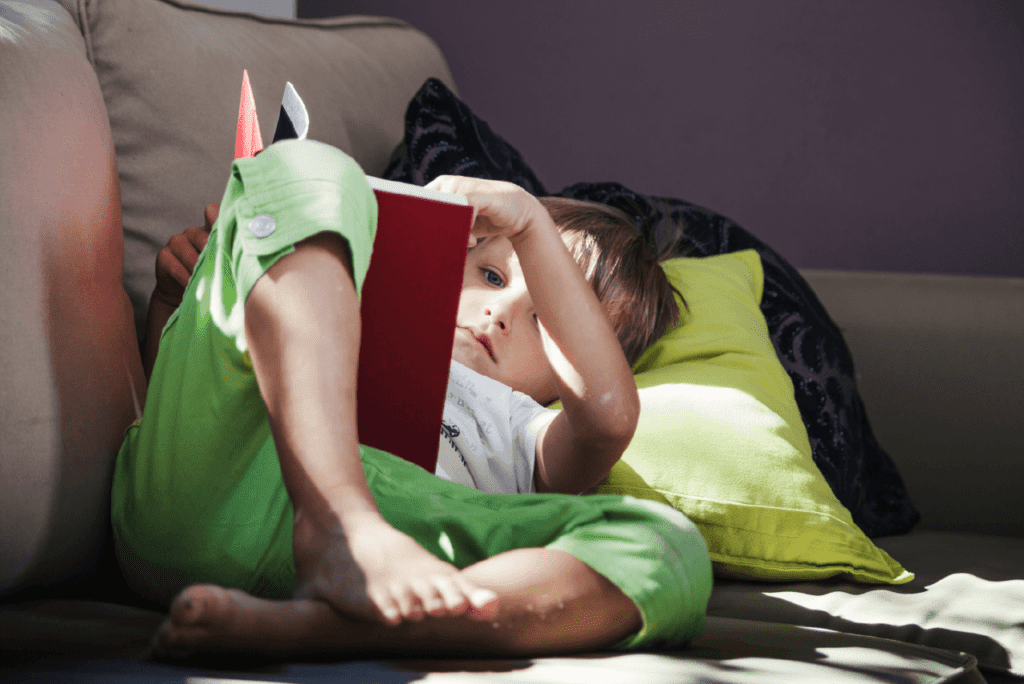 A child in dinosaur pajamas reading a book about prehistoric creatures