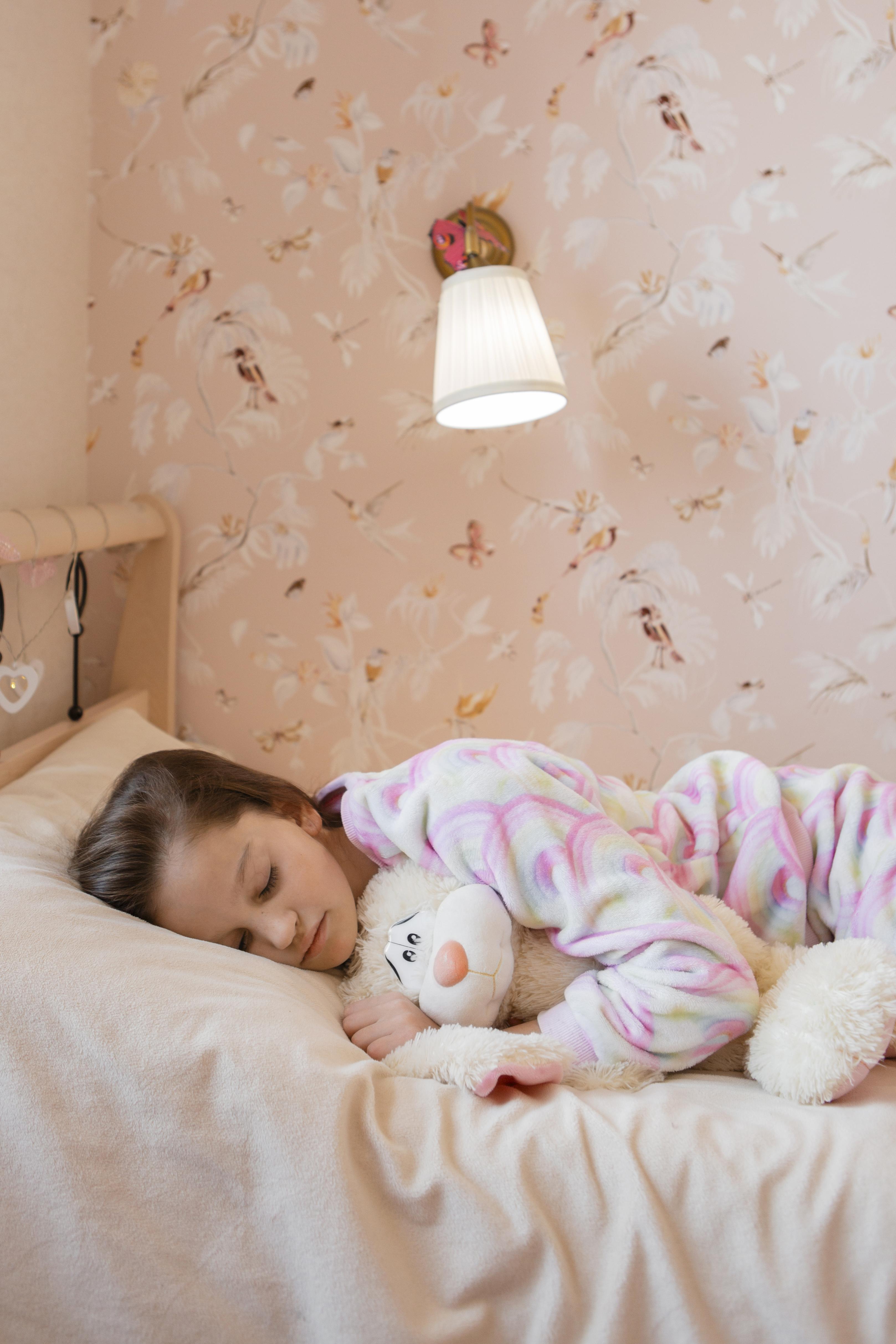 A child sleeping peacefully with a smile, wrapped in pastel colored pajamas