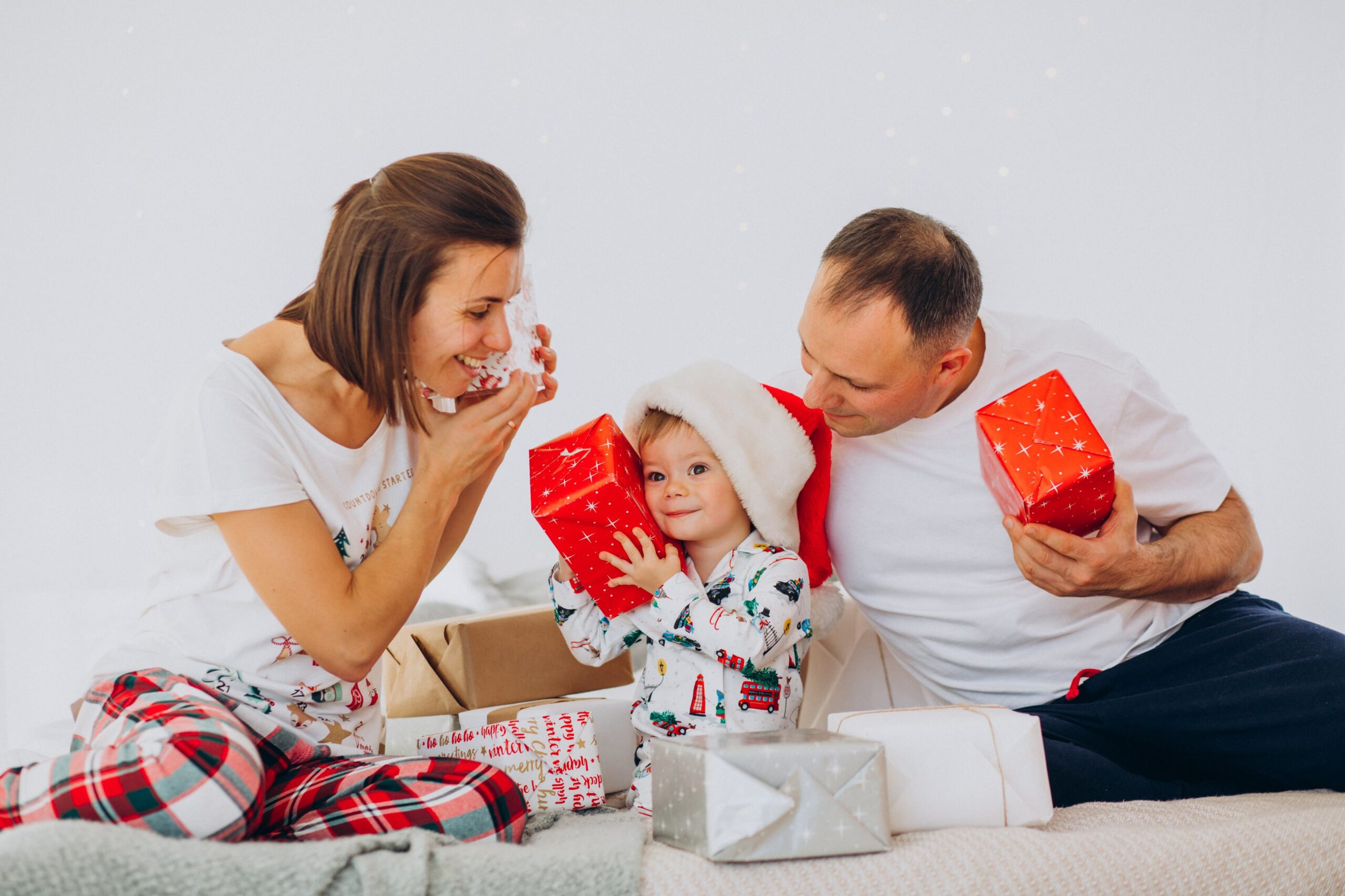 A family in matching holiday-themed pajamas, unwrapping gifts