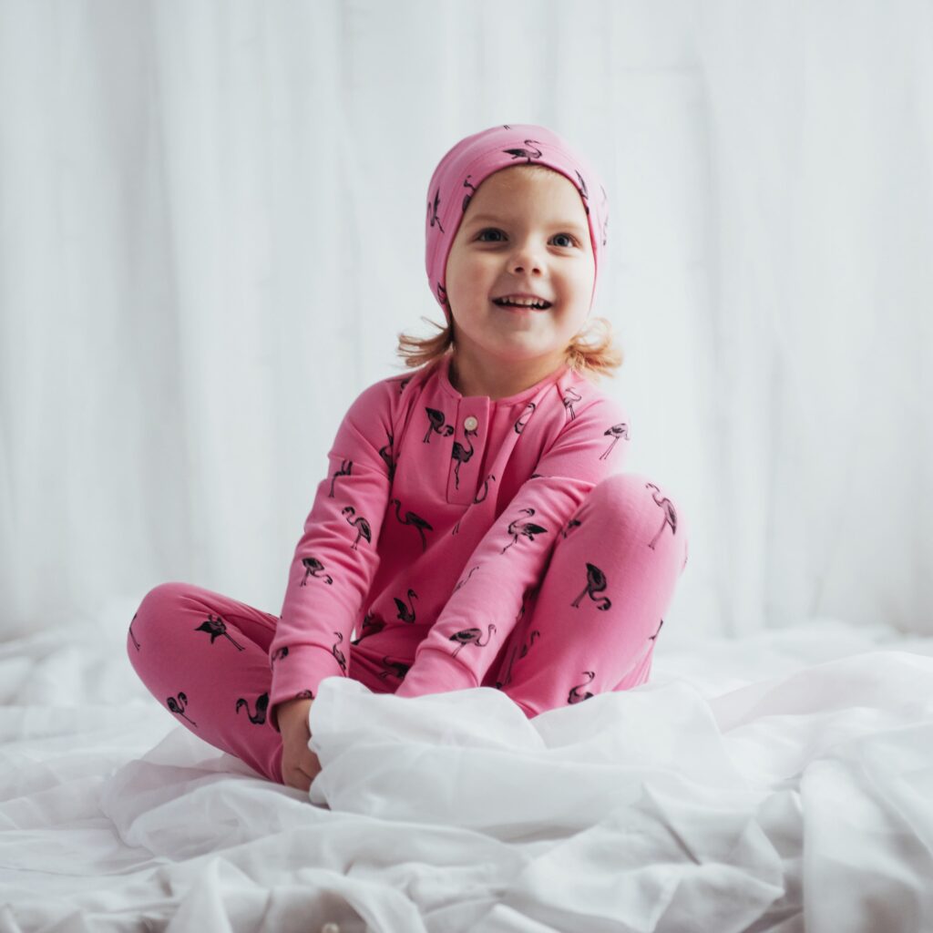 A kid wearing PJs, flaunting a cute bedtime cap, and looking ready for a fairy tale