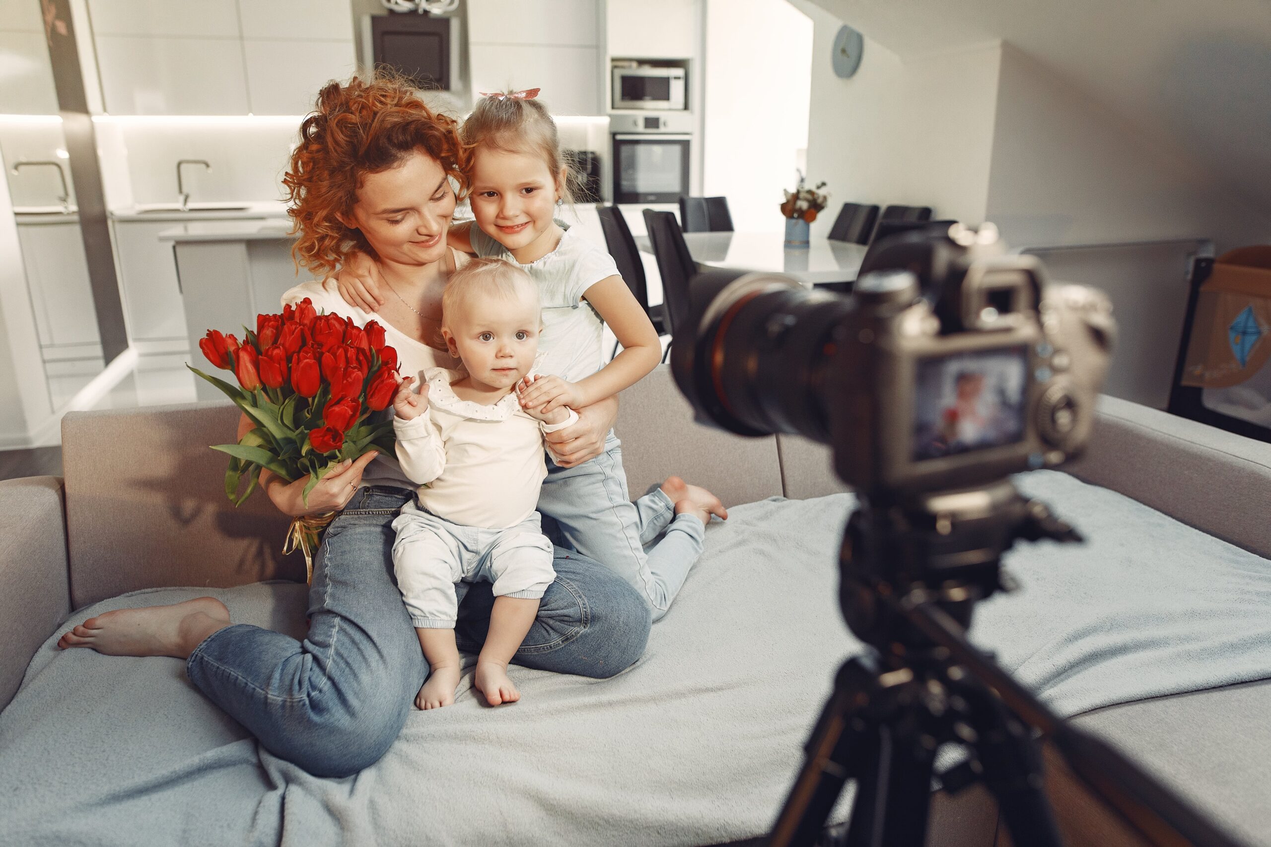 Behind-the-scenes shot laughing parent with a camera, child posing with a wide grin.-min