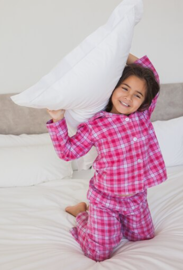 Child lounging comfortably on a bed, wearing cotton pajamas