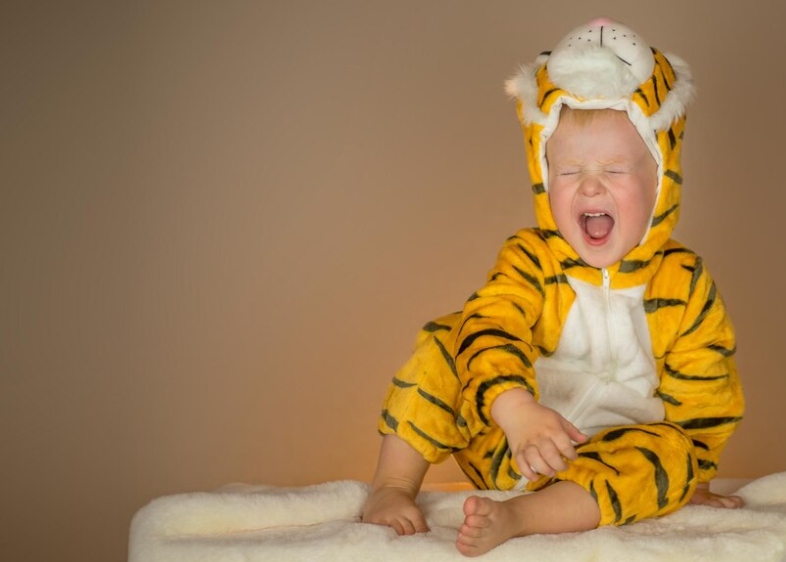 Famous toddler sporting a lion-themed onesie complete with a fluffy mane.