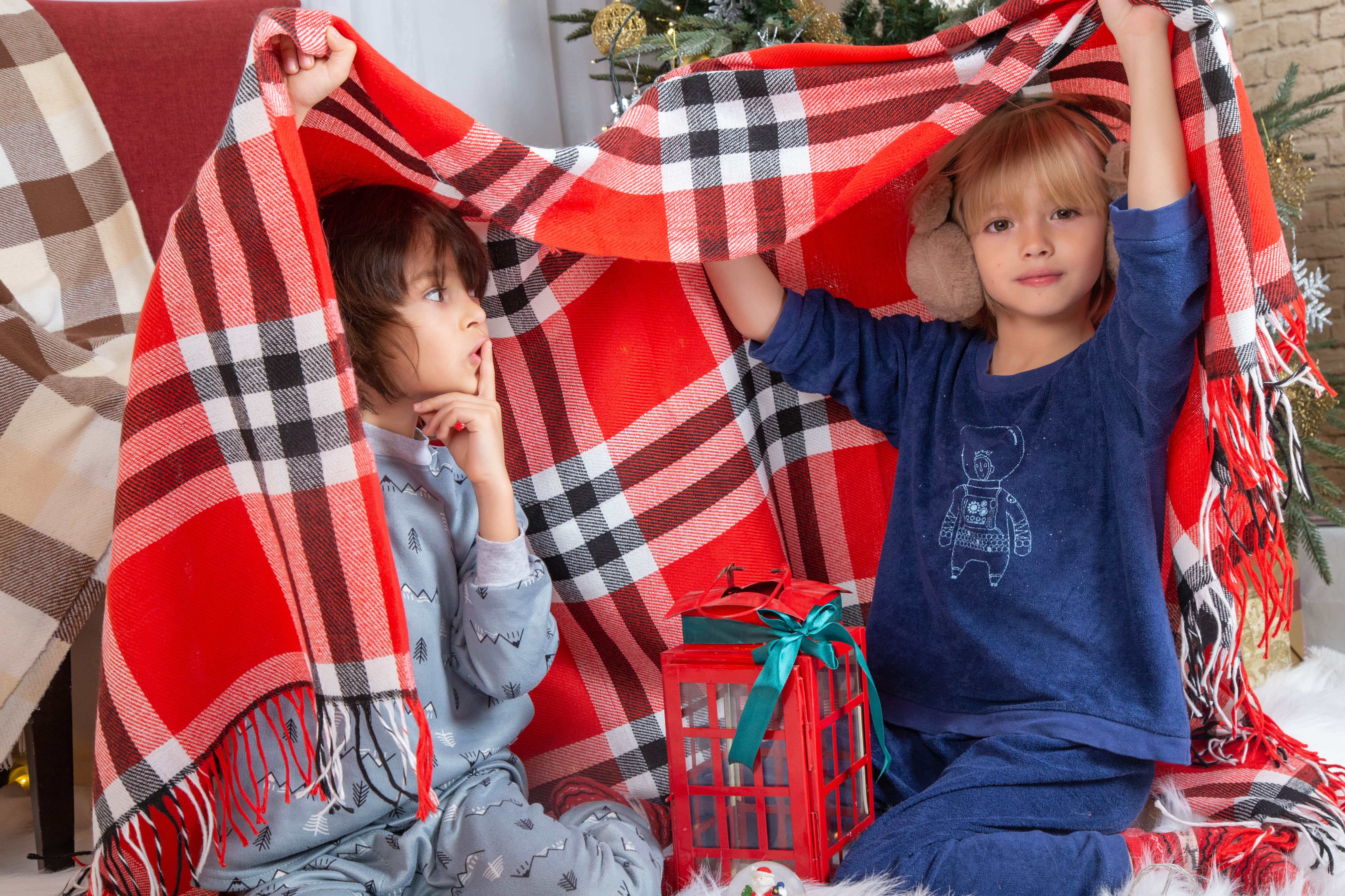 Kid in a tent made of blankets, in their favorite PJs, ready for an adventure