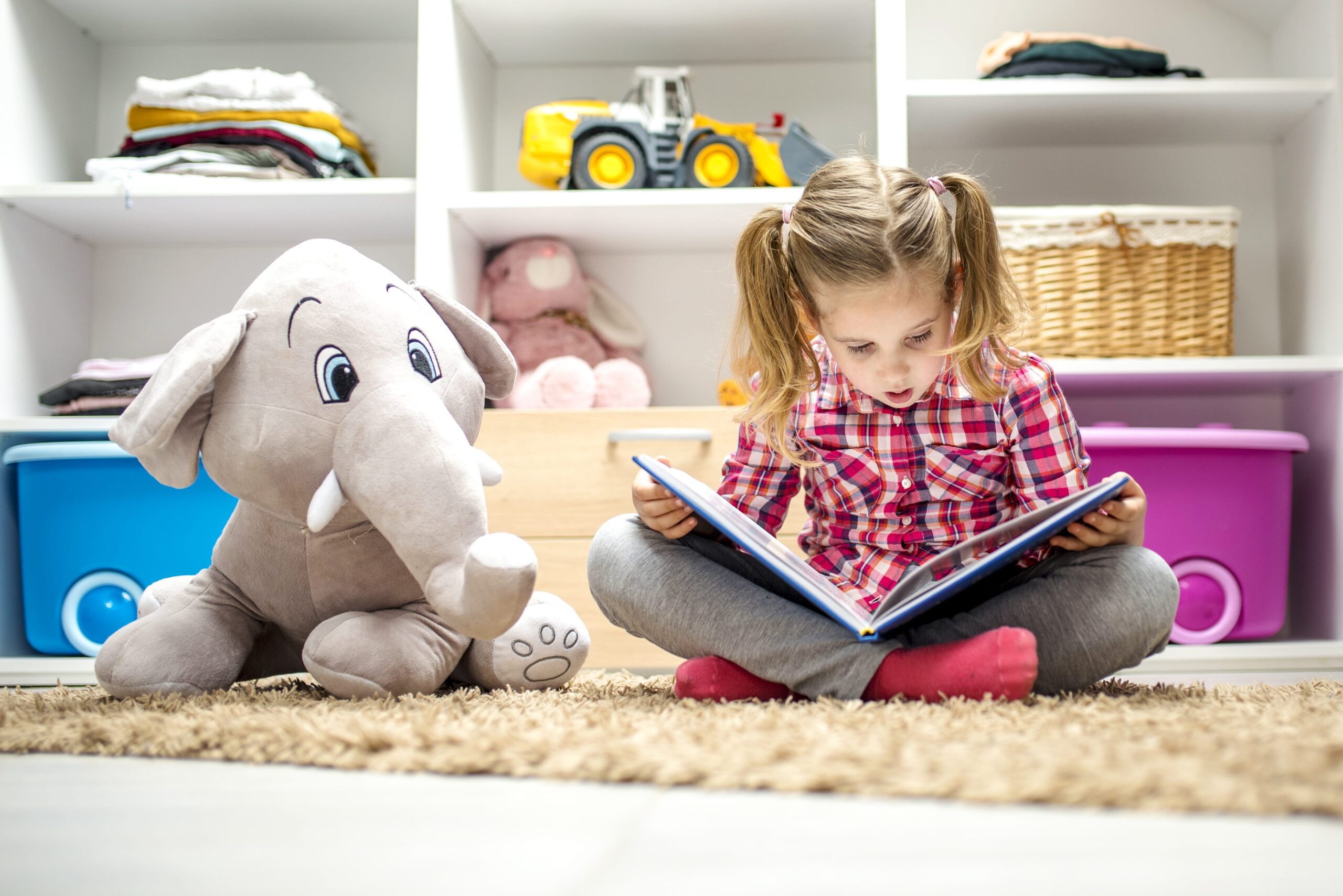 Kid reading a book, surrounded by plush toys, in their PJs