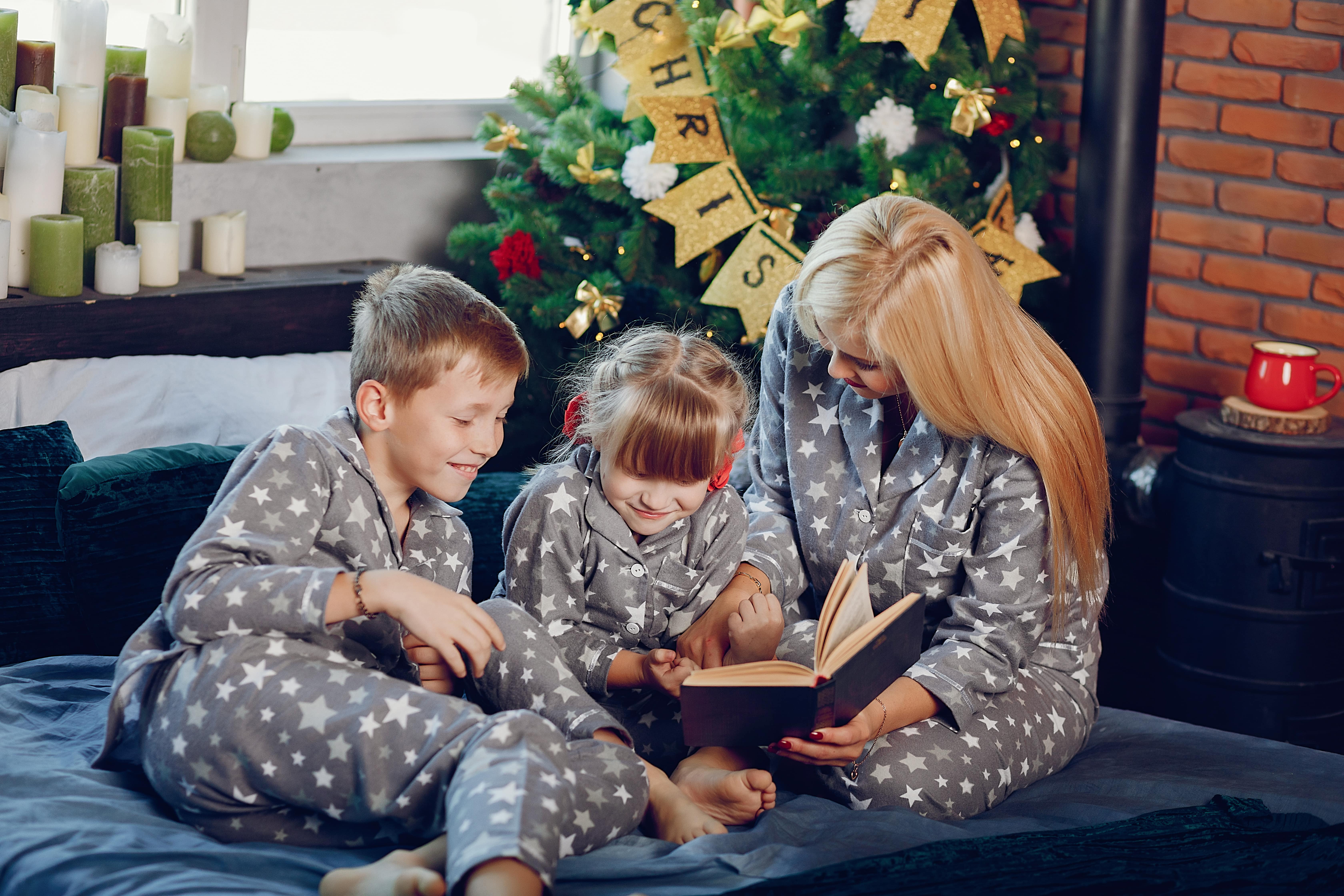 Parent reading a holiday story to kids in pajamas