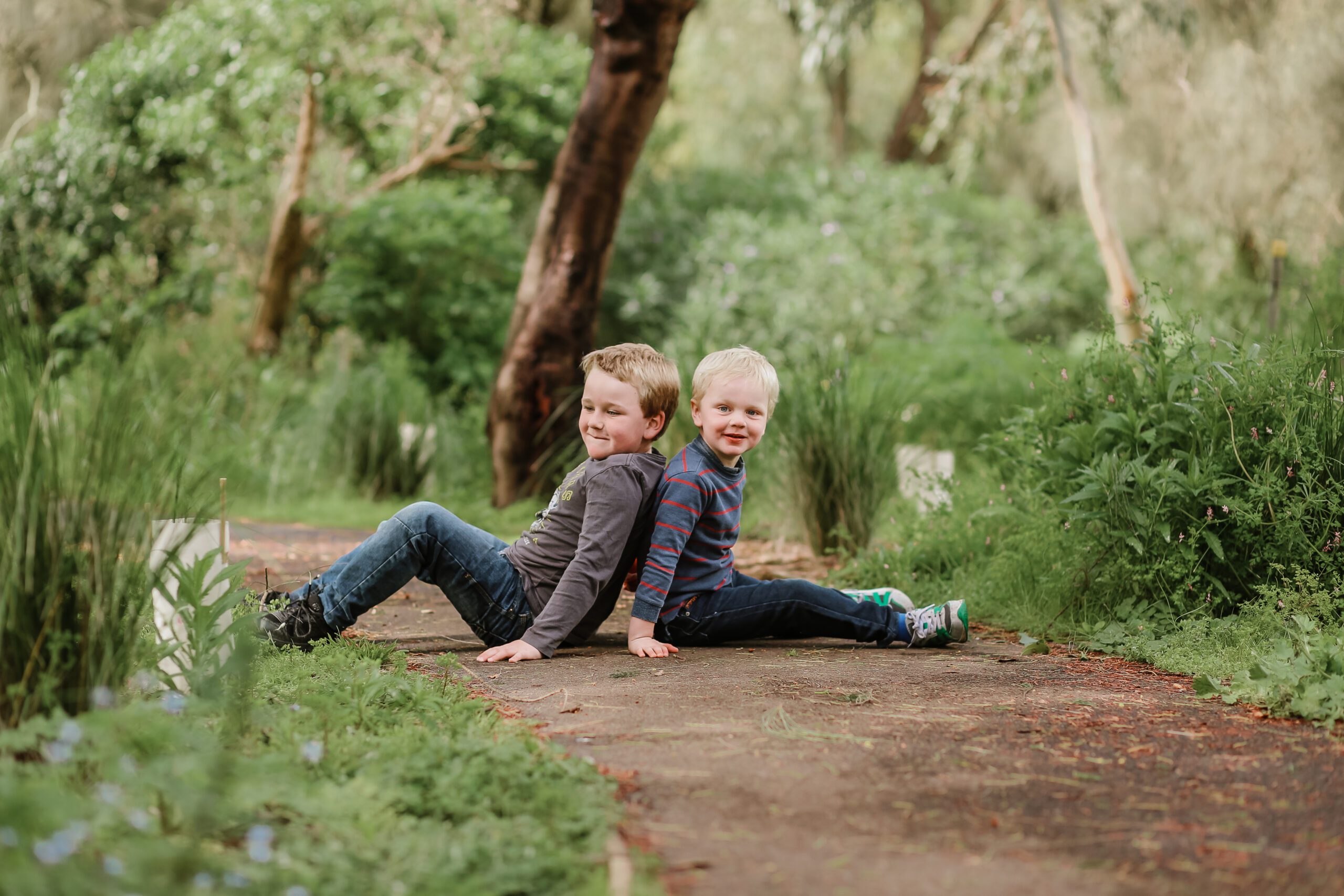 Cute little blonde kids sitting on the ground in a park and playing